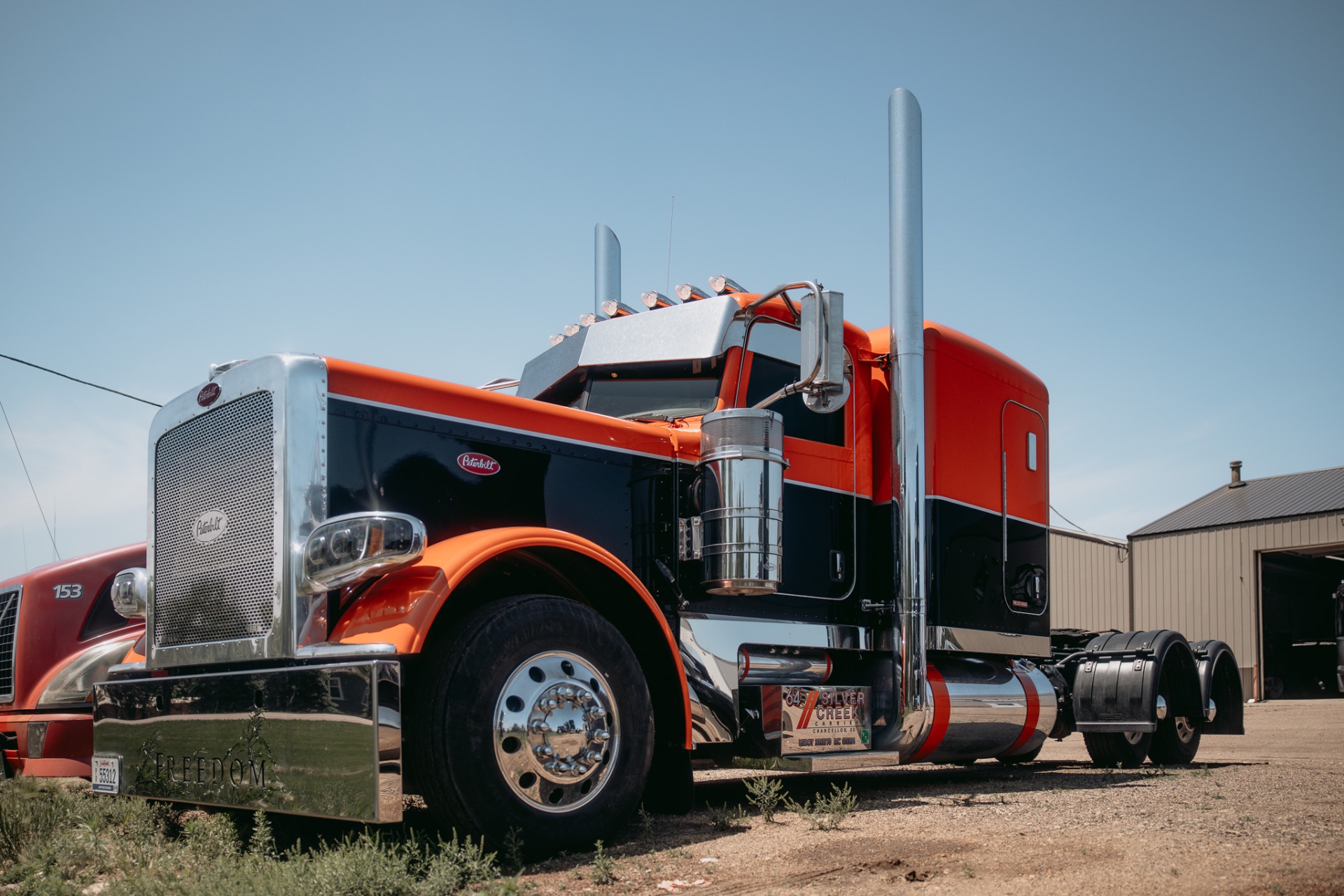 Orange and black Peterbilt outside the shop